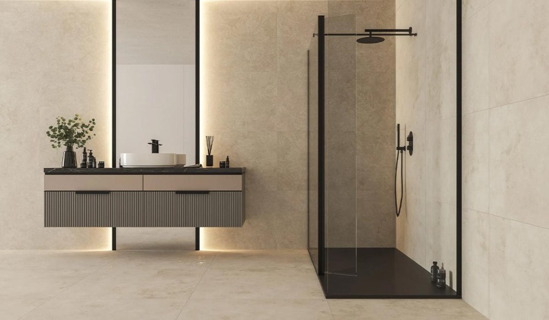 A contemporary bathroom with coordinated cream wall and floor tiles, a charcoal vanity, matte-black fixtures and warm lighting.